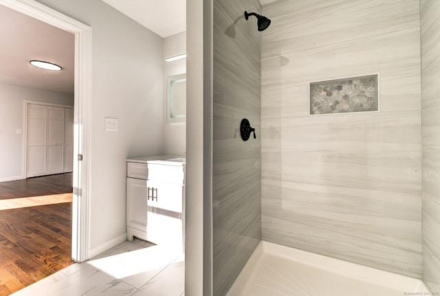 bathroom with wood-type flooring and a tile shower