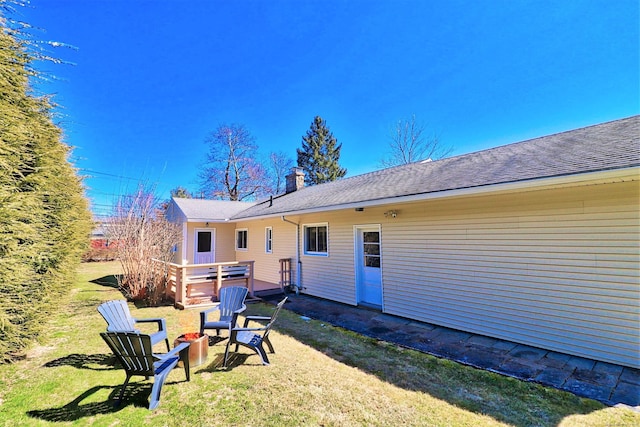 rear view of property with a yard and an outdoor fire pit