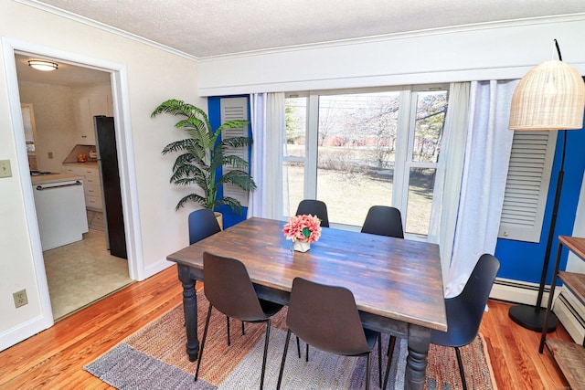 dining space featuring ornamental molding, a textured ceiling, light hardwood / wood-style floors, and a baseboard radiator