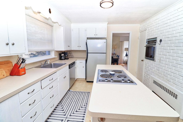 kitchen featuring stainless steel appliances, sink, crown molding, brick wall, and white cabinets