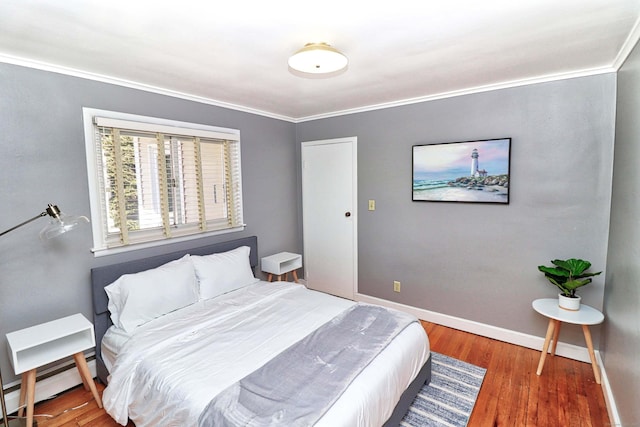 bedroom with hardwood / wood-style flooring, a baseboard radiator, and ornamental molding