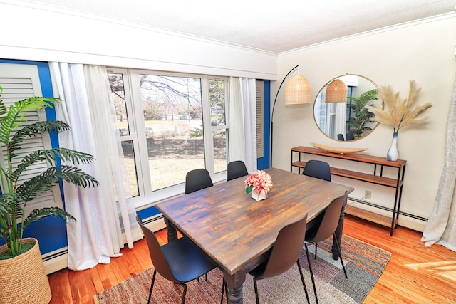 dining space with ornamental molding, hardwood / wood-style floors, and a baseboard heating unit