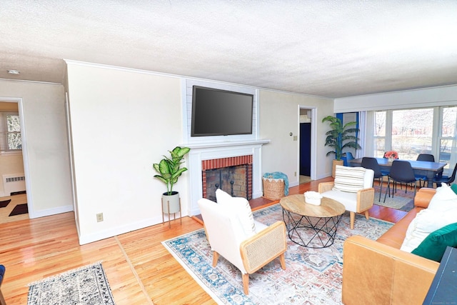 living room featuring crown molding, wood-type flooring, a brick fireplace, a textured ceiling, and radiator