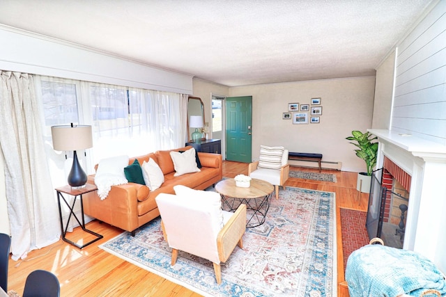 living room with a baseboard heating unit, a textured ceiling, a fireplace, and wood-type flooring