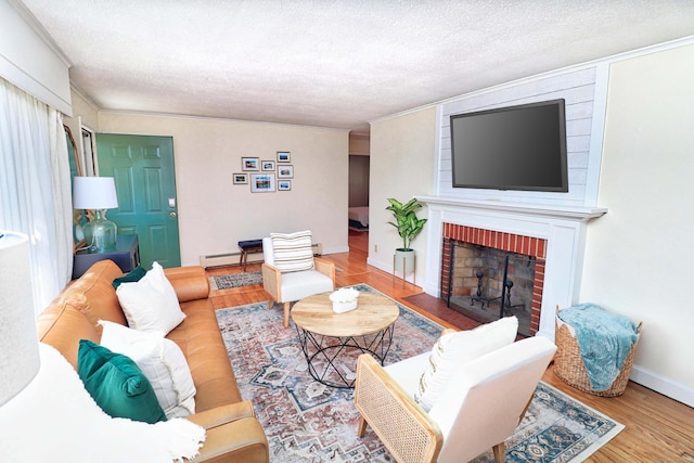 living room with hardwood / wood-style flooring, a fireplace, a textured ceiling, and a baseboard heating unit