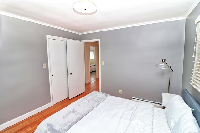 bedroom featuring crown molding, a closet, baseboard heating, and light hardwood / wood-style floors