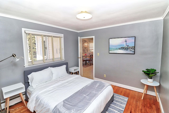 bedroom with crown molding, a baseboard radiator, and hardwood / wood-style flooring