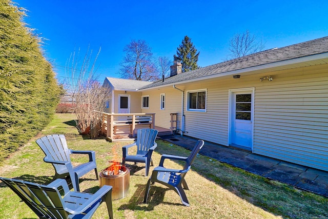 back of house with a fire pit and a lawn