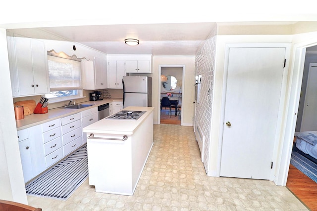 kitchen featuring stainless steel appliances, a kitchen island, sink, and white cabinets