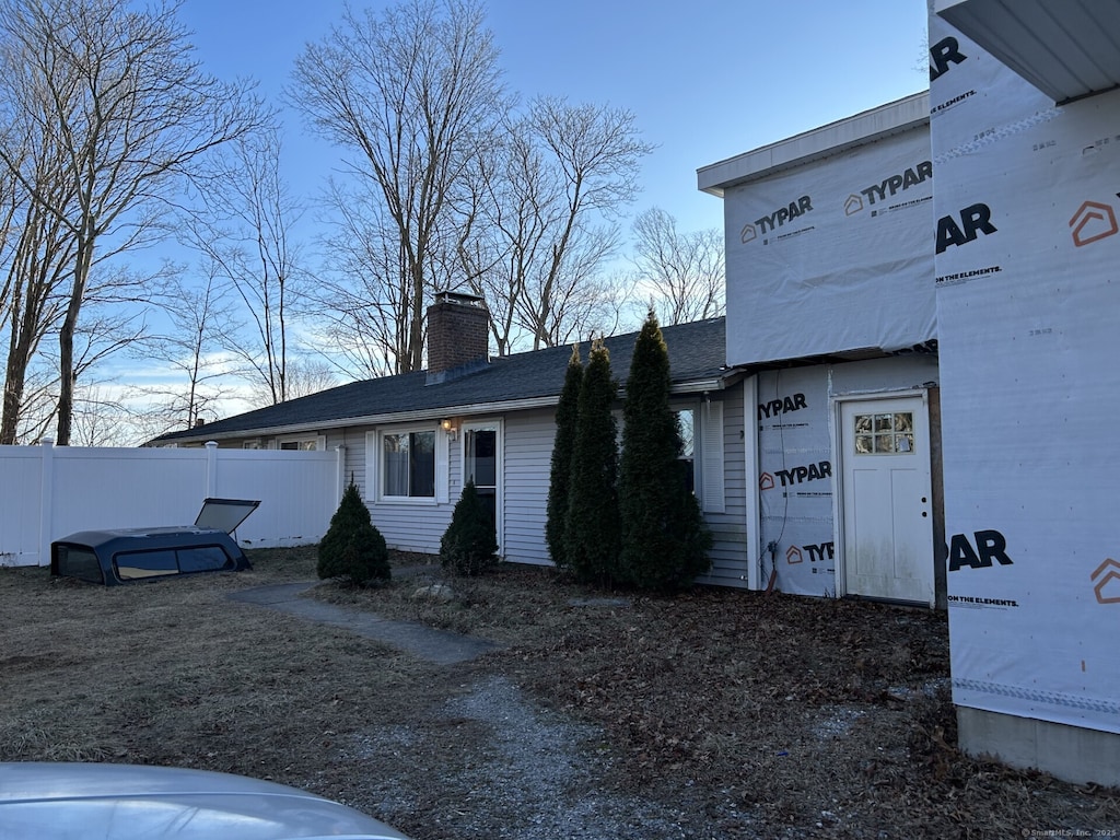 view of front of house with a chimney and fence