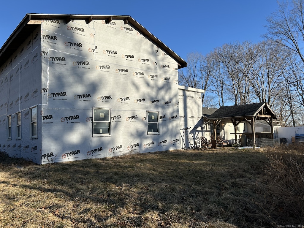 view of side of property featuring crawl space, a lawn, and a gazebo