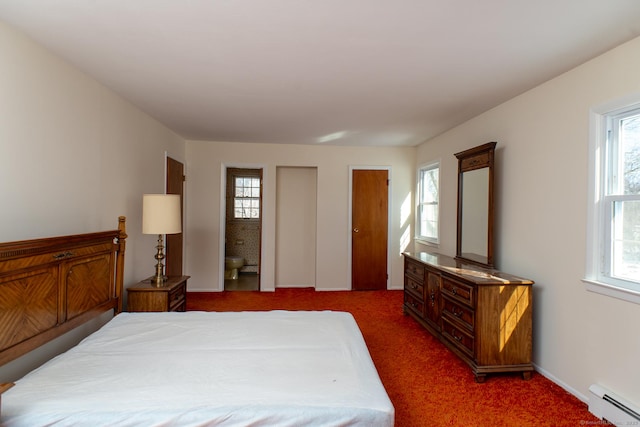 bedroom with a baseboard radiator, multiple windows, dark colored carpet, and two closets