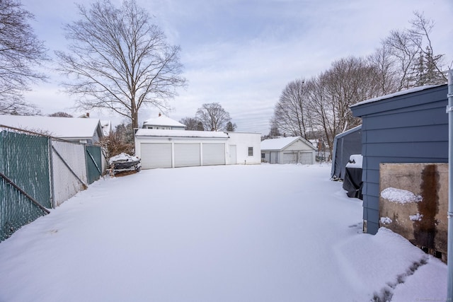 yard covered in snow featuring an outbuilding and a garage