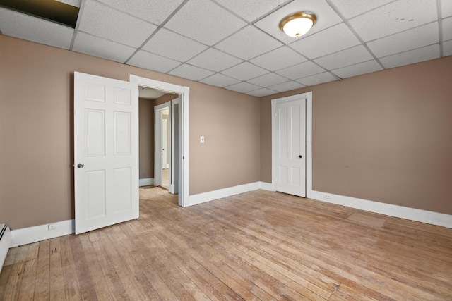 interior space featuring a baseboard heating unit, light hardwood / wood-style flooring, and a paneled ceiling