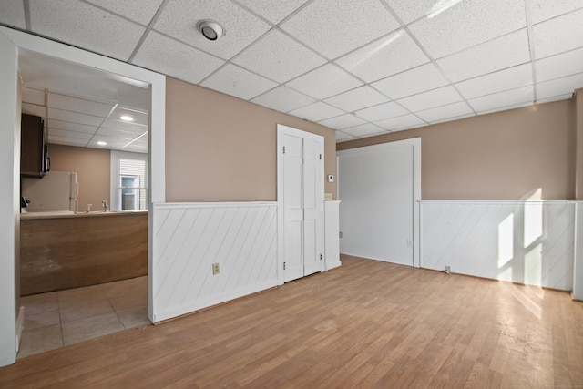 spare room featuring a paneled ceiling and light hardwood / wood-style flooring