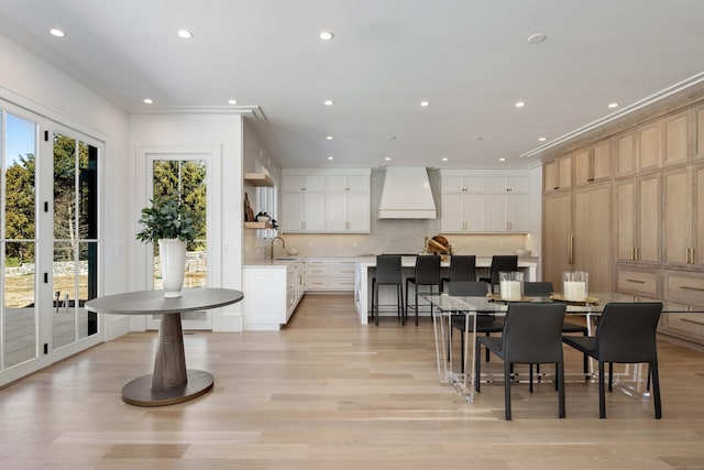 dining room featuring sink, ornamental molding, light hardwood / wood-style floors, and french doors