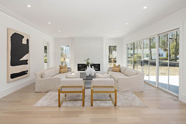 living room with ornamental molding, plenty of natural light, a premium fireplace, and light hardwood / wood-style floors