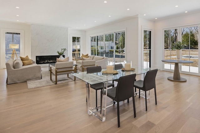 dining space featuring crown molding, a fireplace, and light wood-type flooring