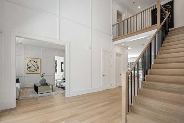 stairs with hardwood / wood-style flooring and a towering ceiling