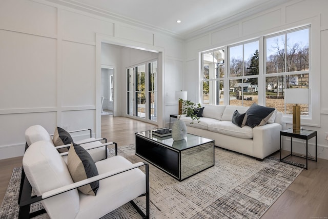 living room featuring crown molding, plenty of natural light, and light wood-type flooring