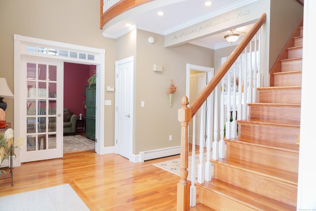 entryway featuring hardwood / wood-style flooring, crown molding, baseboard heating, and french doors