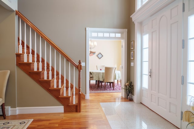 foyer with a healthy amount of sunlight, a chandelier, wood-type flooring, and a high ceiling