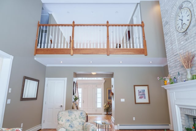 living room featuring a high ceiling, crown molding, a brick fireplace, and baseboard heating