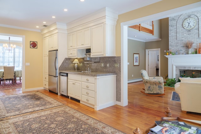 kitchen featuring crown molding, tasteful backsplash, appliances with stainless steel finishes, a fireplace, and a baseboard heating unit