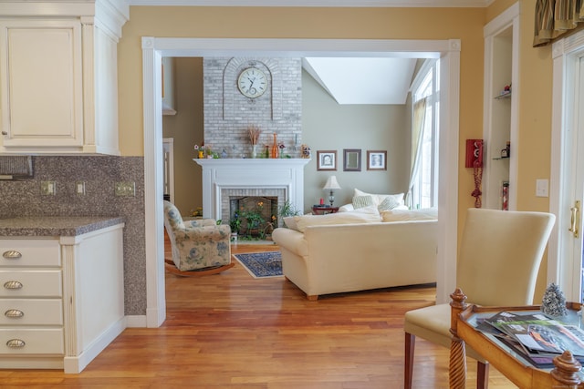 living room featuring a brick fireplace, light hardwood / wood-style flooring, and built in features