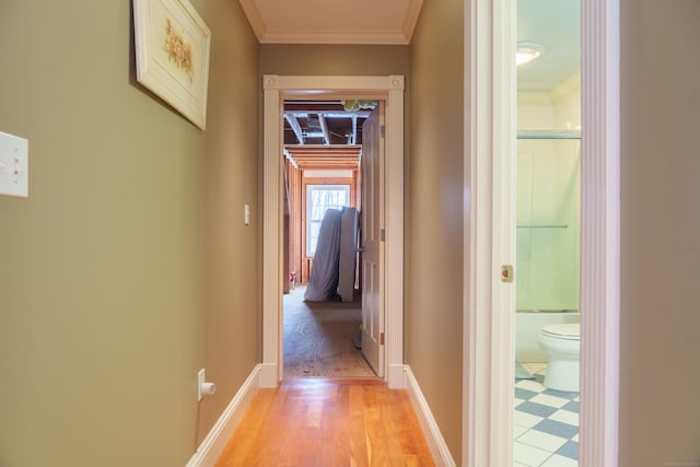 corridor with ornamental molding and light hardwood / wood-style flooring