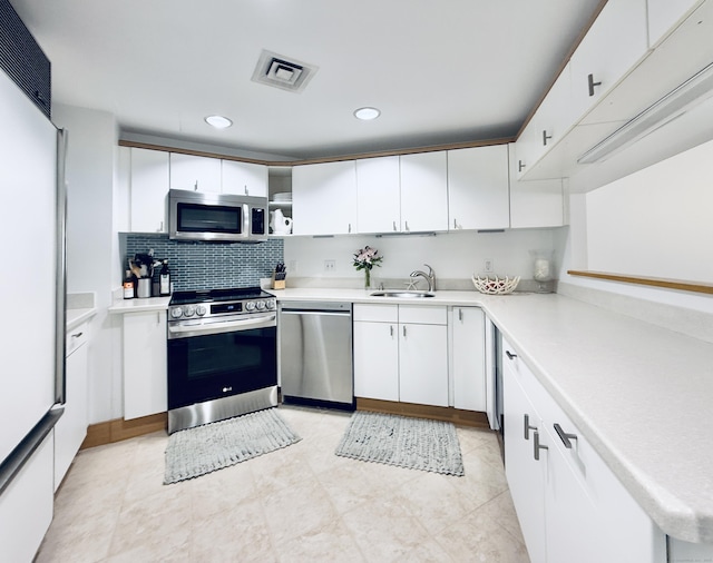 kitchen featuring tasteful backsplash, appliances with stainless steel finishes, sink, and white cabinets