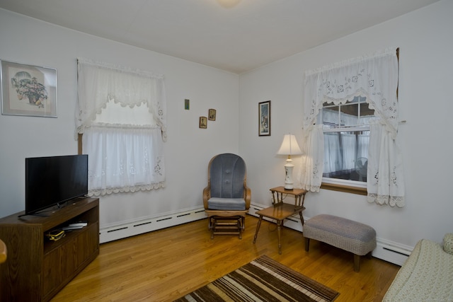 living area with baseboard heating and light hardwood / wood-style flooring