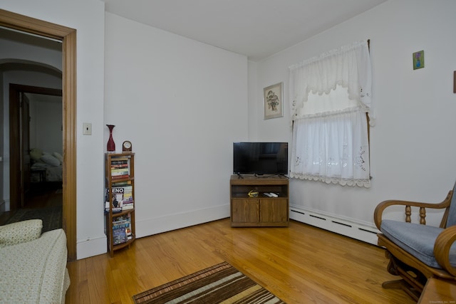 living area featuring a baseboard radiator and hardwood / wood-style floors