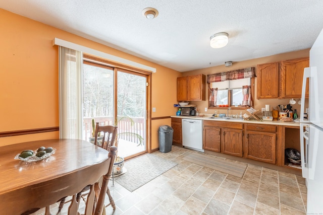 kitchen featuring white appliances, sink, and a textured ceiling