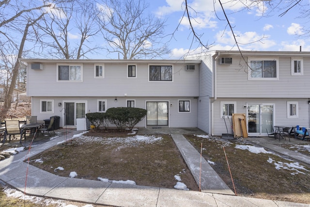 snow covered back of property with a patio