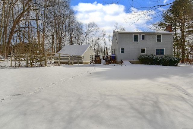 snow covered rear of property with a wooden deck