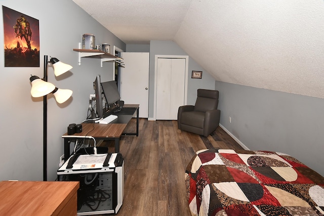 bedroom featuring dark wood-type flooring, lofted ceiling, and a textured ceiling