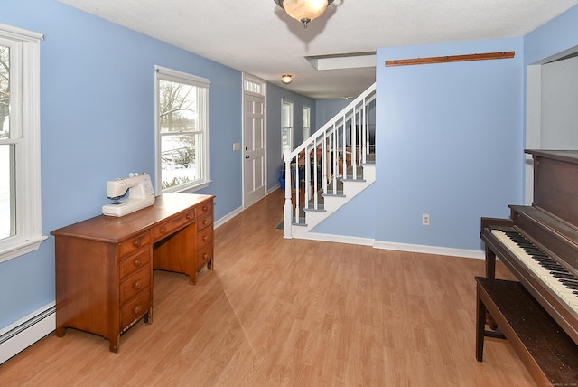 foyer entrance featuring a baseboard radiator, a textured ceiling, and light wood-type flooring