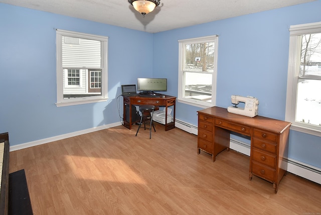 office space featuring a baseboard radiator, plenty of natural light, and light hardwood / wood-style floors