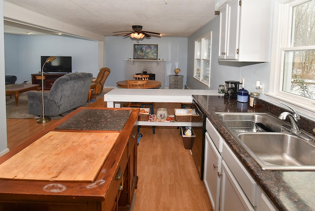 kitchen featuring sink, white cabinets, ceiling fan, a textured ceiling, and light hardwood / wood-style flooring