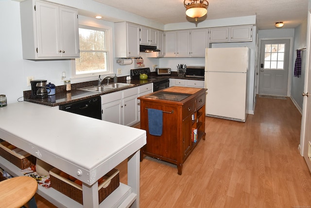 kitchen featuring sink, black appliances, light hardwood / wood-style floors, and a healthy amount of sunlight