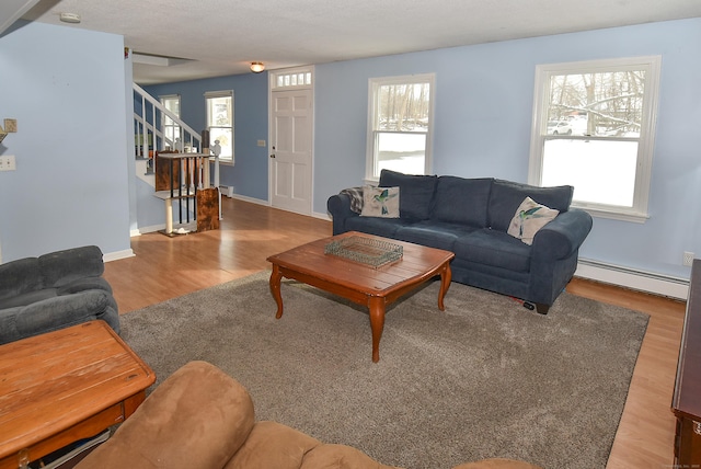 living room featuring a healthy amount of sunlight, wood-type flooring, and a baseboard heating unit