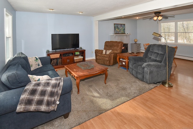 living room with hardwood / wood-style floors, a textured ceiling, and baseboard heating