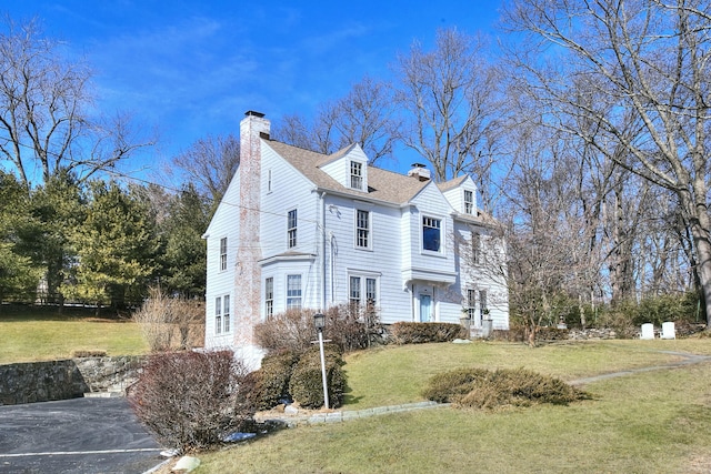 view of property exterior with roof with shingles, a yard, and a chimney