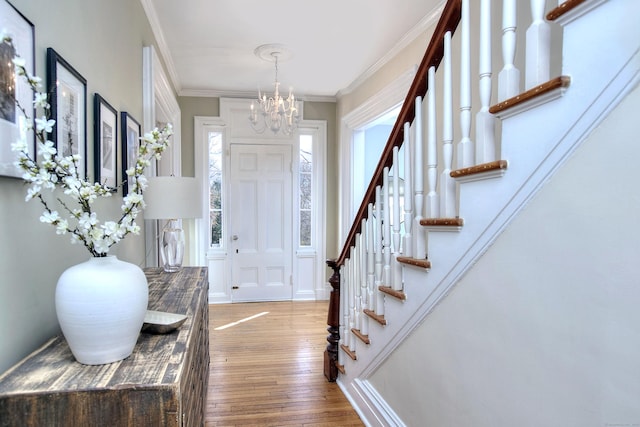 entryway featuring hardwood / wood-style flooring, stairway, ornamental molding, and a notable chandelier