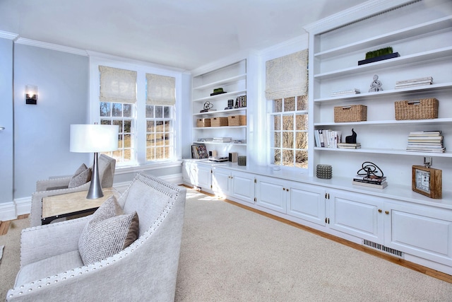 sitting room featuring visible vents, baseboards, light wood-style floors, built in features, and crown molding