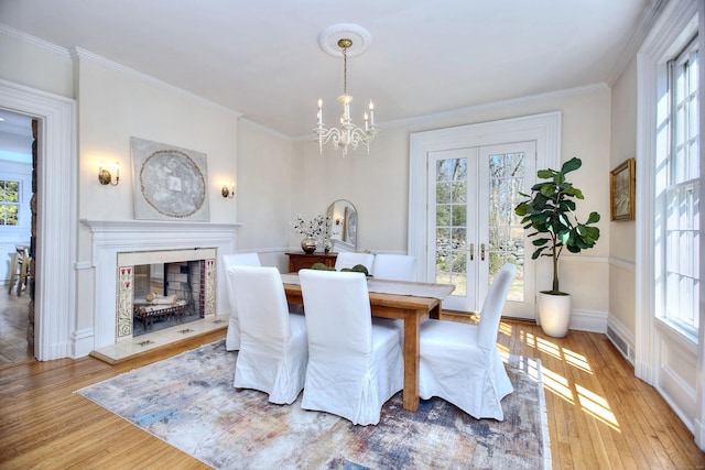 dining room featuring a high end fireplace, wood-type flooring, and crown molding