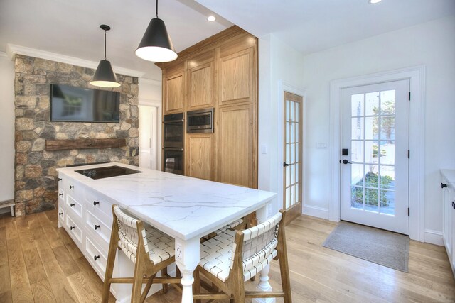 kitchen featuring light stone counters, a healthy amount of sunlight, light wood finished floors, and black appliances