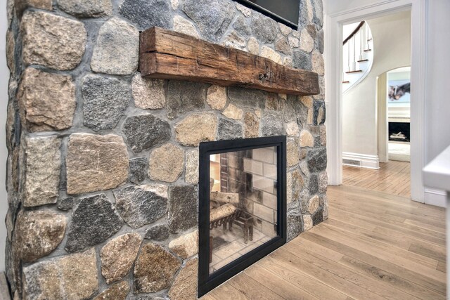 room details with a stone fireplace and wood finished floors