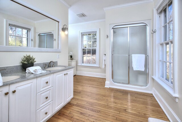 full bath featuring a stall shower, wood-type flooring, ornamental molding, and a sink